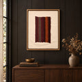 Framed vintage kilim fragment wall art in burgundy, gray, green, orange hanging on a dark wall above a wooden console